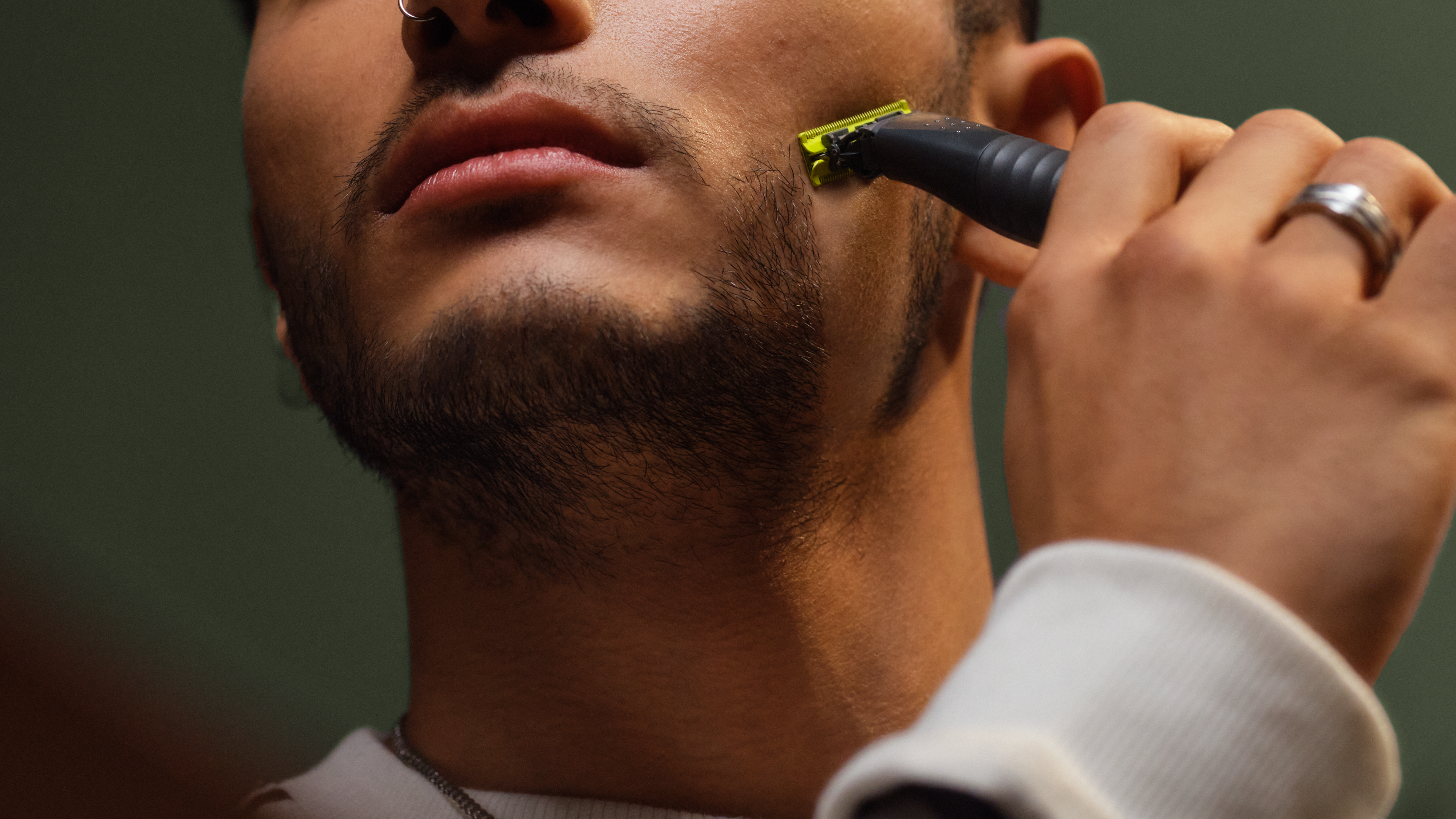 Eine Nahaufnahme eines jungen Mannes, der seinen Bart mit einem Philips OneBlade rasiert.