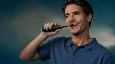 A middle-aged man brushes his teeth using a Philips Next-Generation DiamondClean electric toothbrush.