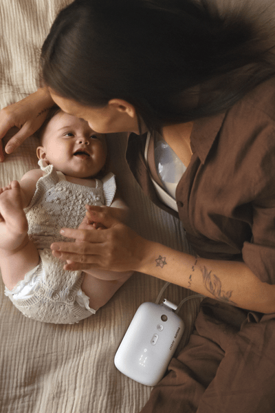 Mum on bed with baby breast pumping