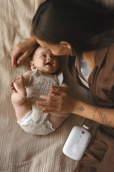 Mom on bed with baby breast pumping