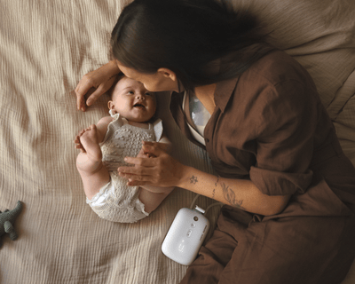 Мама на ліжку з молоковідсмоктувачем і дитиною