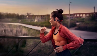 Atleet die tijdens een hardloopsessie buiten bone-conduction-hoofdtelefoons gebruikt.