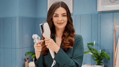 Жінка укладає волосся плойкою