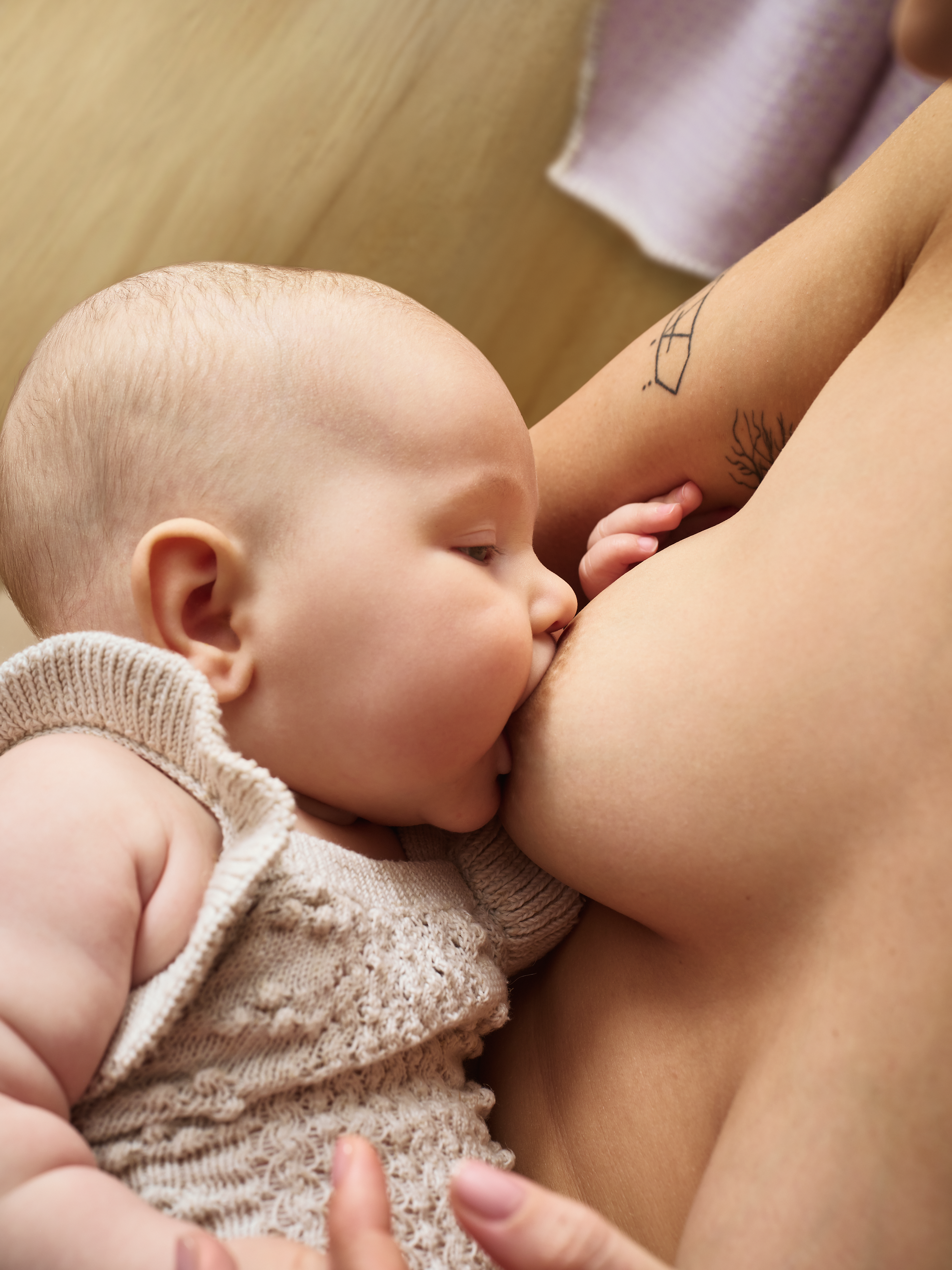 Mamá en una cama extrayendo leche junto a un bebé