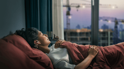 Couple sleeping, with the woman wearing Philips Sleep Headphones