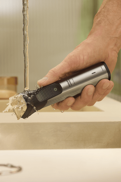hairy arm holding Philips Norelco All-in-one Trimmer 9000 in hand under the water