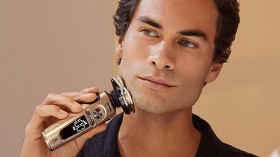 Muškarac brije lice električnim rotacijskim brijačem