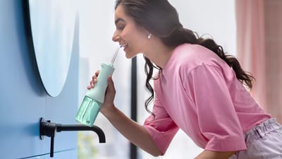 Kobieta czyszcząca przestrzenie międzyzębowe za pomocą irygatora do zębów Philips