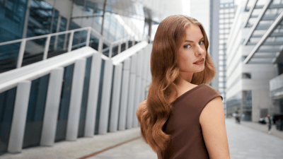 Fundal arhitectural modern cu o persoană care prezintă în centrul atenției părul lung și ondulat.