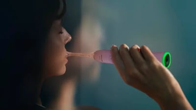 A brunette woman brushes her teeth using a Philips Next-Generation DiamondClean electric toothbrush.