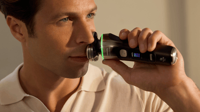 Close-up image of a man shaving his beard with a silver Philips rotary shaver.