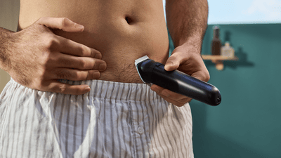 A man uses a Philips Bodygroom shaver to shave hair below his belly button.