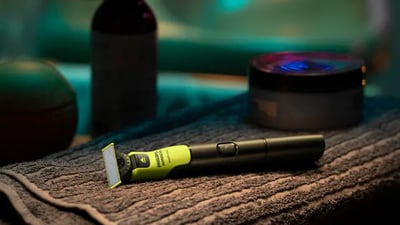 A Philips OneBlade rests on a towel in a dimly lit room.