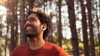 Man using Philips wireless sports earbuds while training outdoors, enjoying music during an active workout.