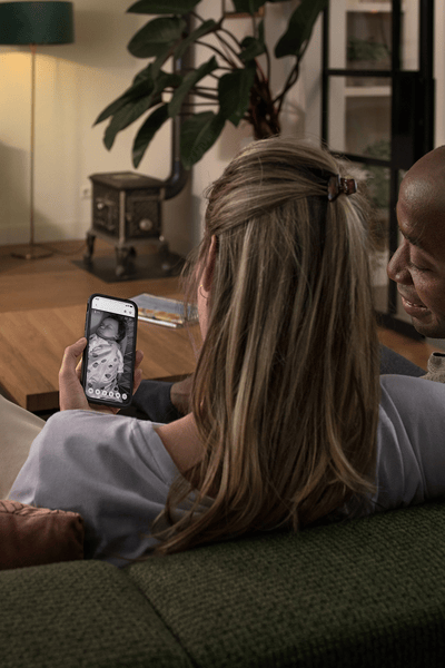A couple watching their baby via their phone and the baby monitor