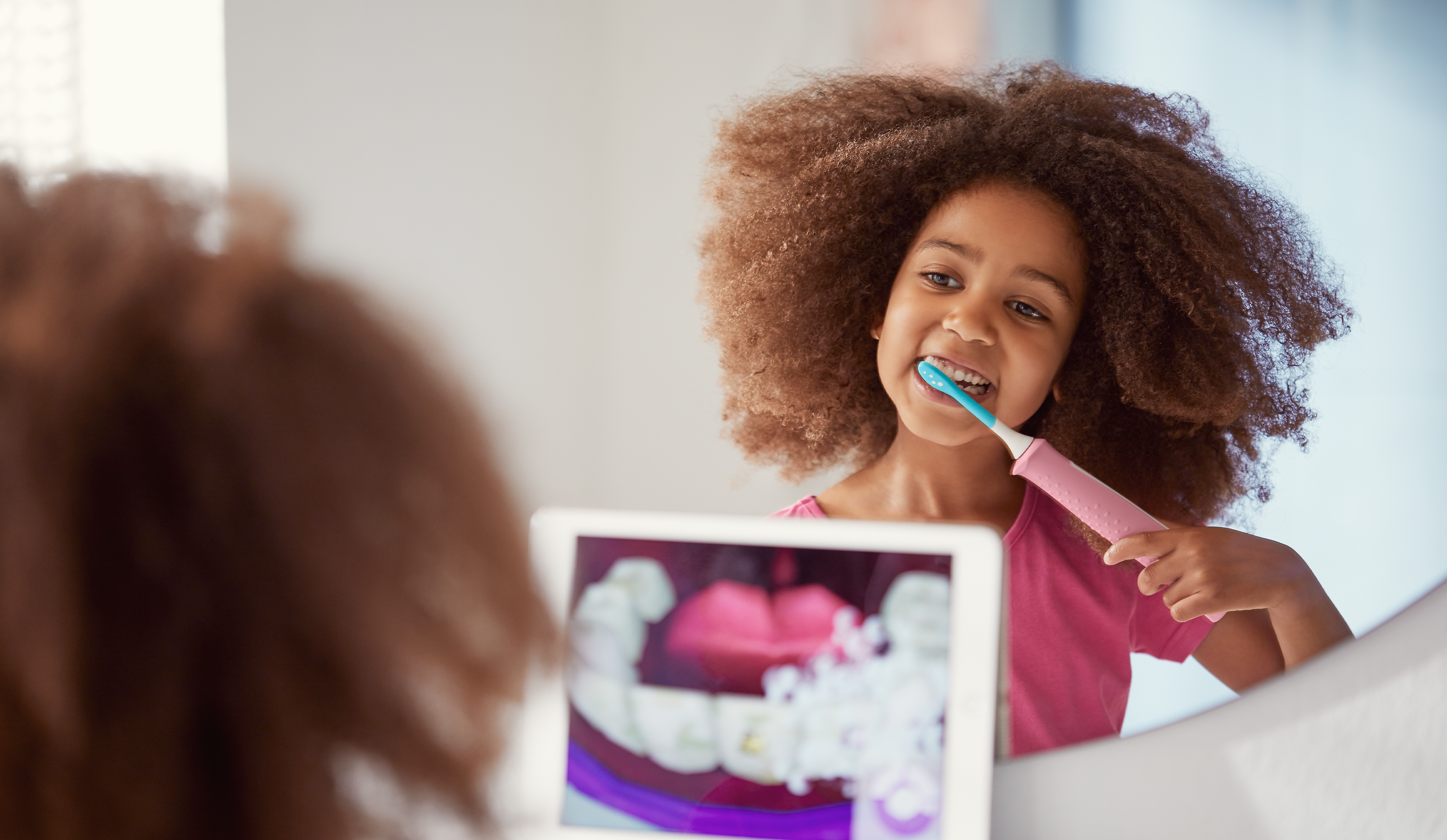 Girl using a Sonicare For Kids power toothbrush