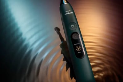 A close-up of a Philips Next-Generation DiamondClean toothbrush against a rippled blue and orange background.