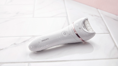 A product image of a white Philips epilator on a white tiled surface.