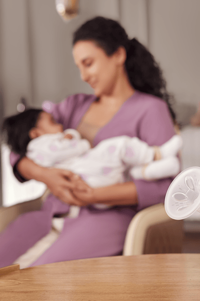 Mãe na cama com o bebê extraindo leite