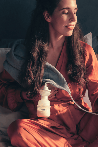 Mom on bed with baby breast pumping