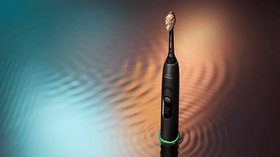 A Philips Next-Generation DiamondClean electric toothbrush against a rippled blue and orange background.