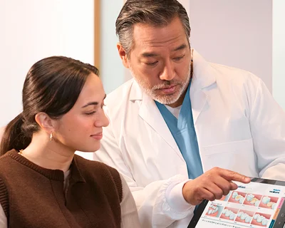 Woman sitting in chair being shown information by dentist.