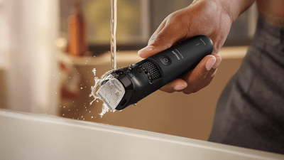 Product close-up of a Philips beard trimmer being cleaned under water.