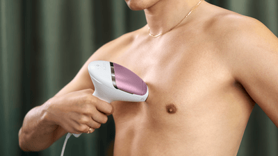 A man uses a Philips Lumea IPL device to remove hair on his chest.