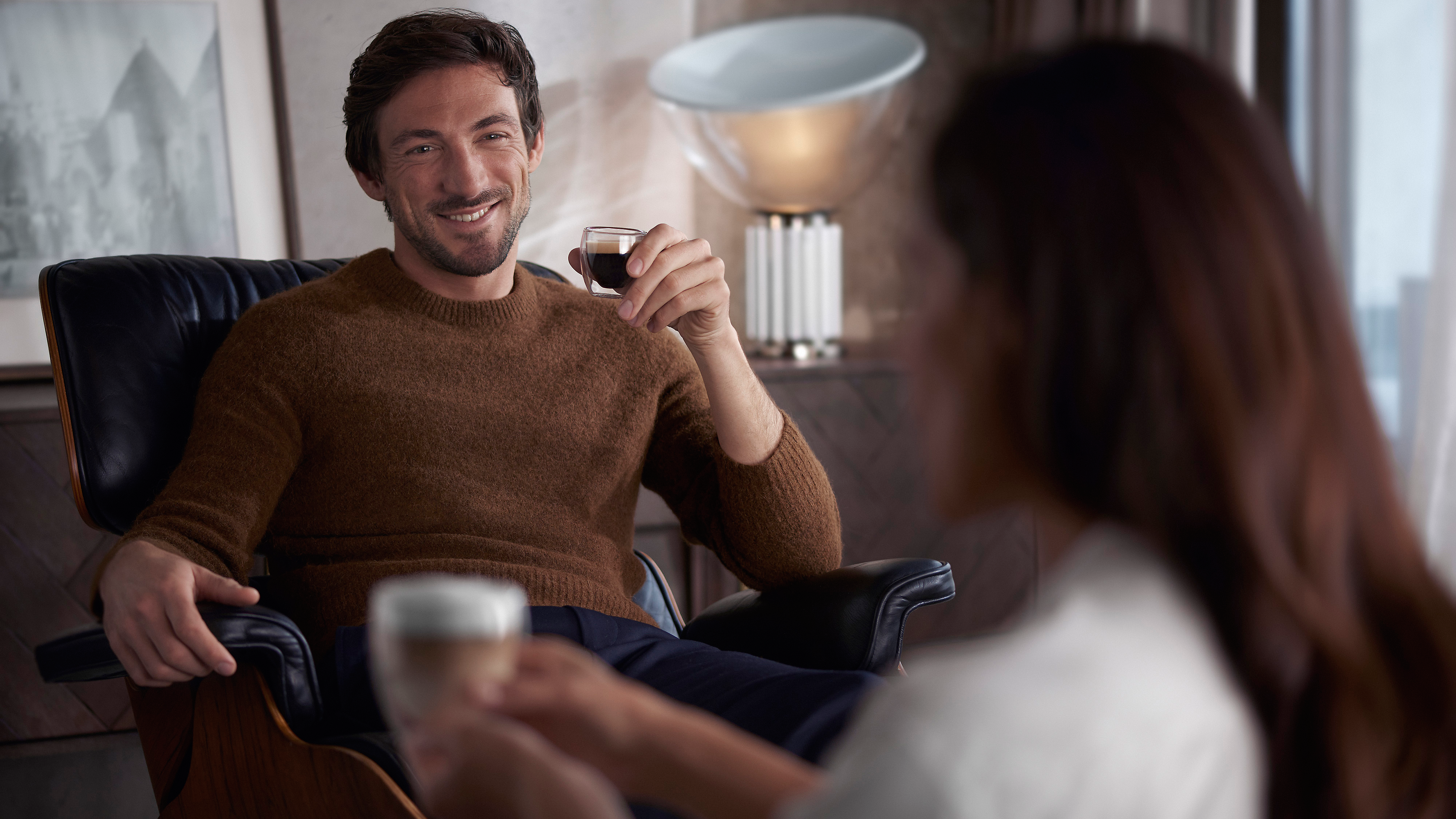 Muž s pekne tvarovanou bradou sa usmieva v kaviarni