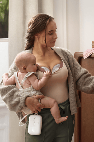 Mother pumping breast milk hands-free while multi-tasking