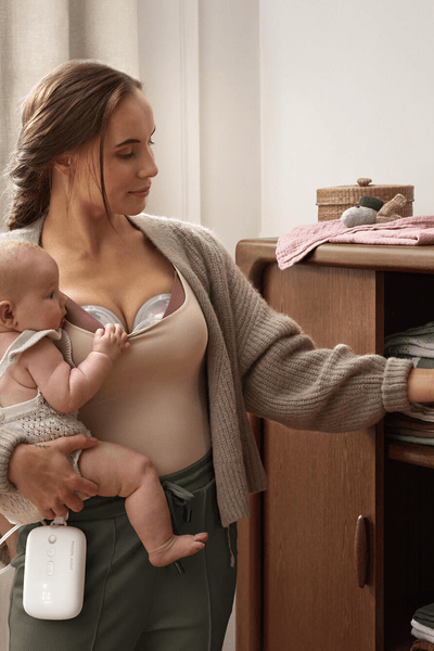 Mother pumping breast milk hands-free while multi-tasking