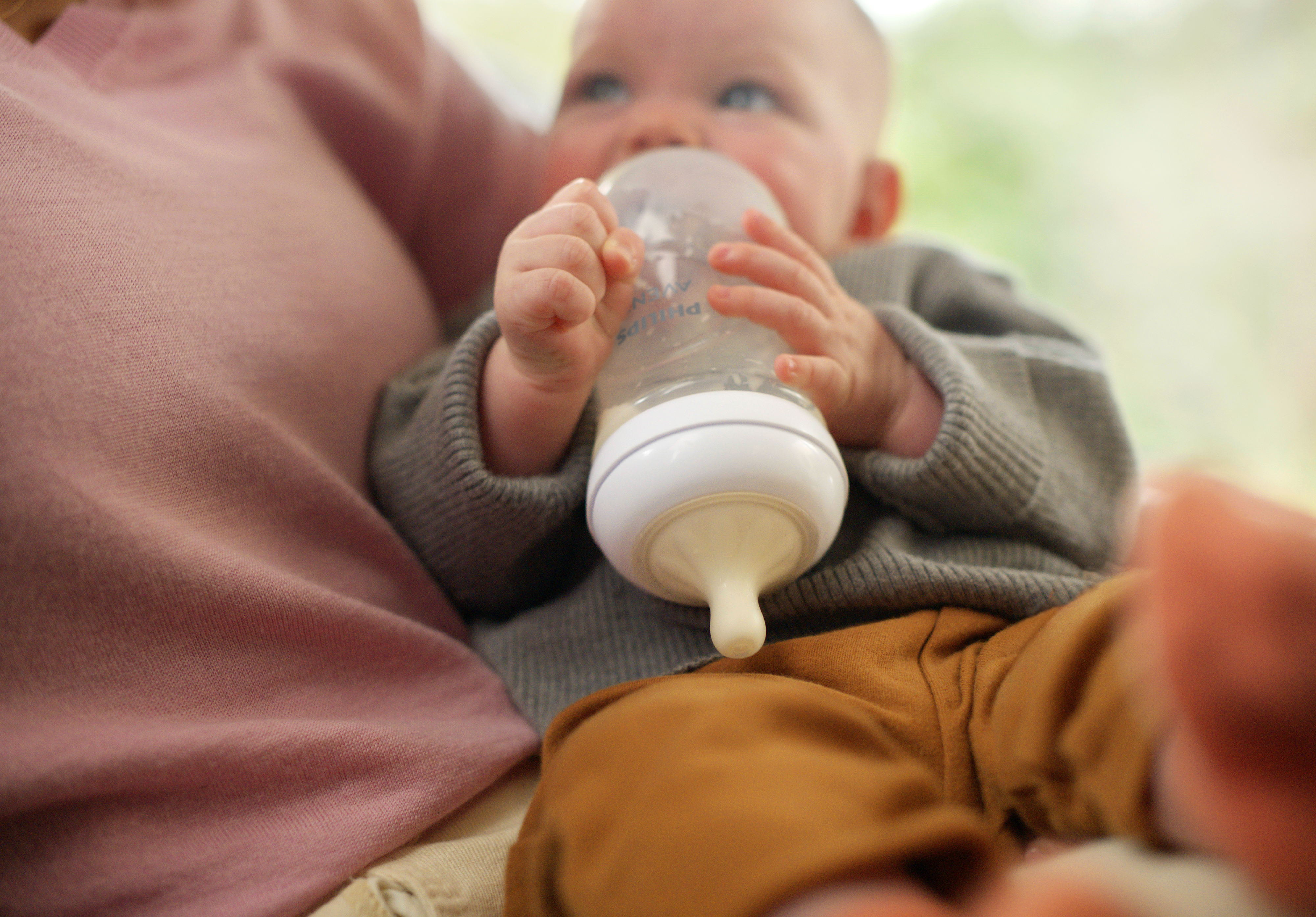 A newborn holds his Philips Avent Natural Response baby bottle upside down after a feed.