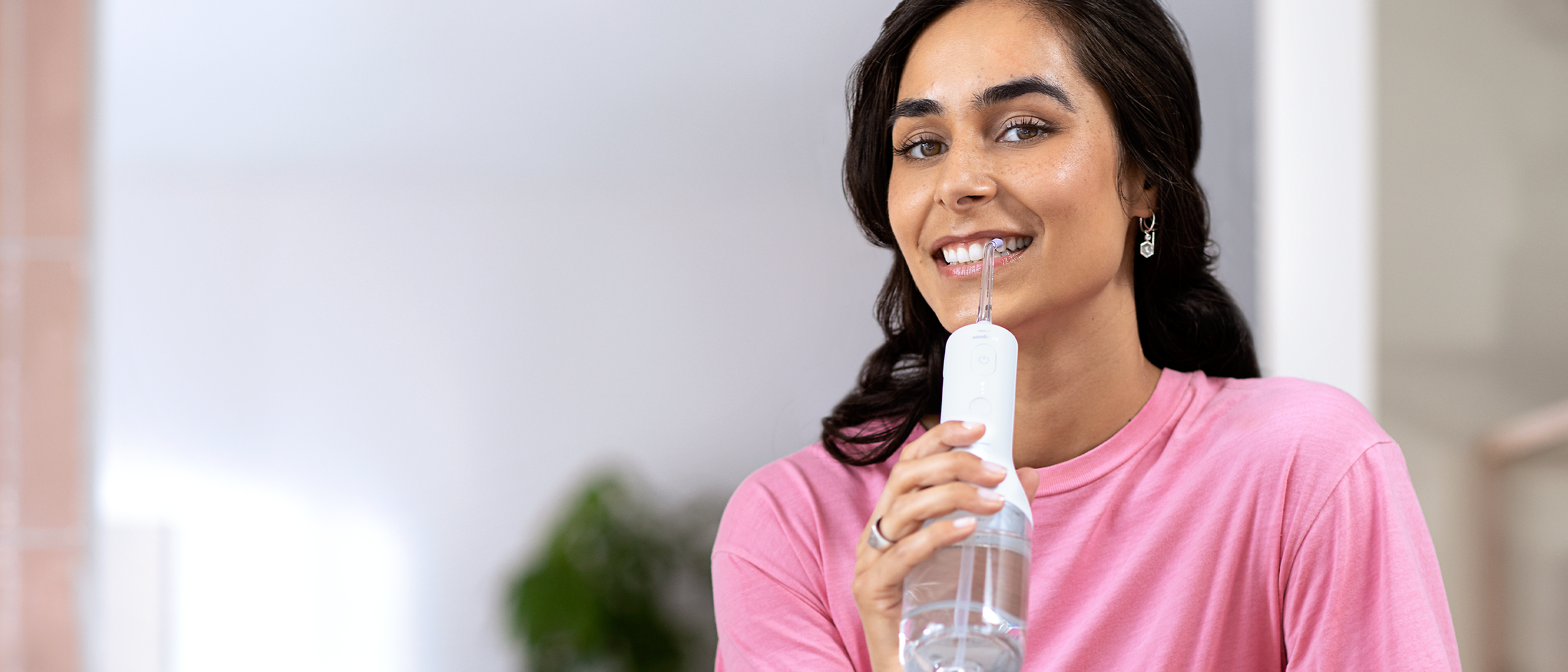 A woman using a Philips Sonicare Cordless Power Flosser.