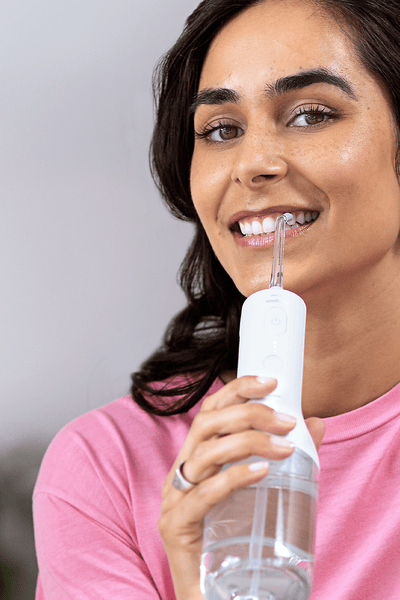 A woman using a Philips Sonicare Cordless Power Flosser.