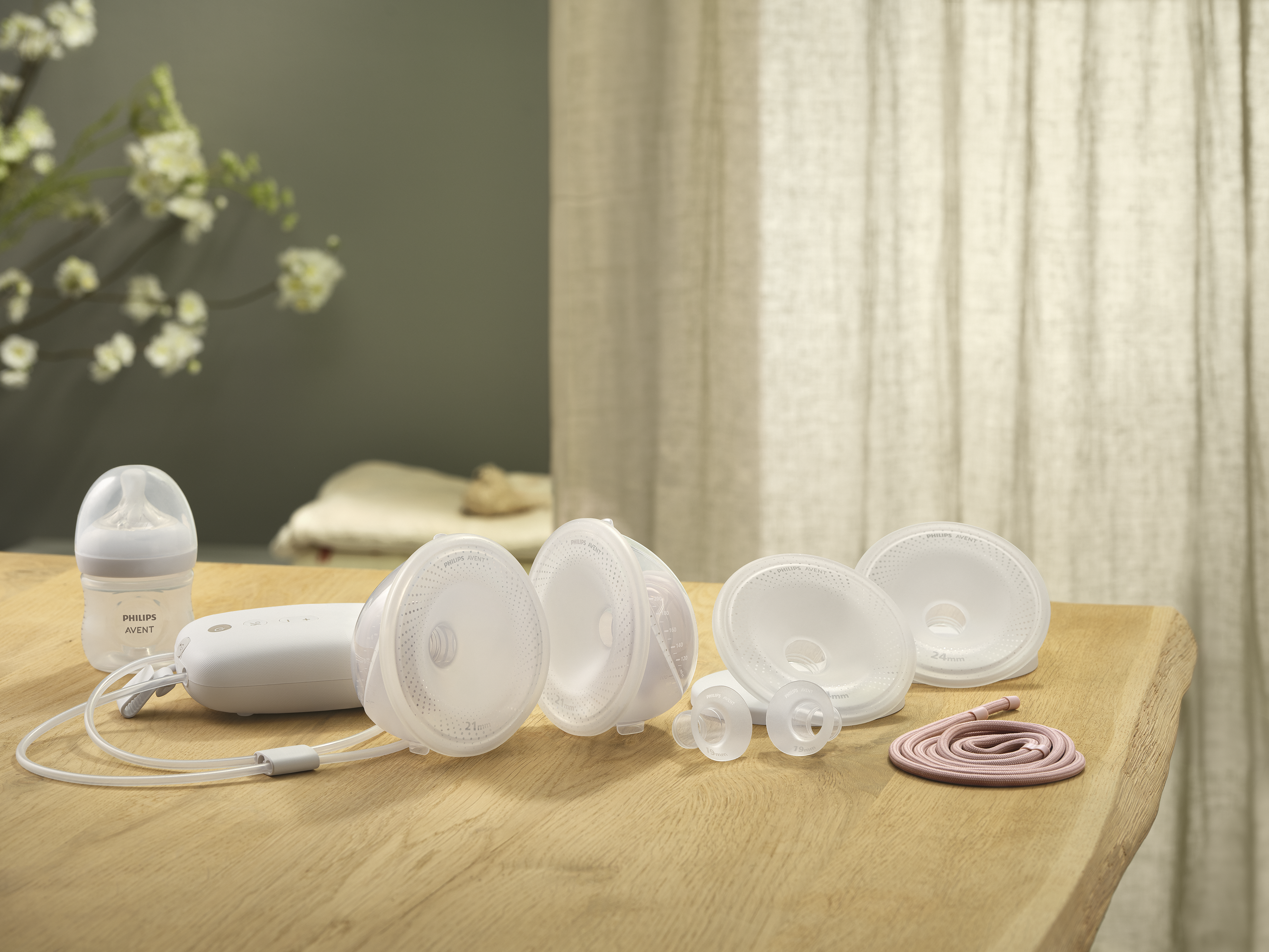 A hands-free Philips breast pump and a Philips baby bottle lying on a wooden table.
