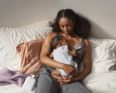 Mama su kūdikiu ant lovos naudoja pientraukį