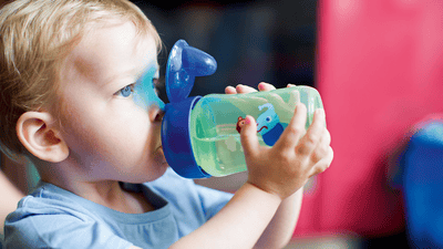 Criança pequena bebendo feliz de um copo