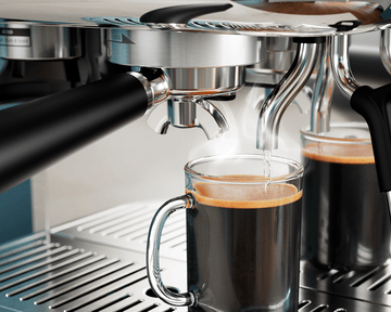 Nalievanie espressa do skleneného hrnčeka, stúpajúca para