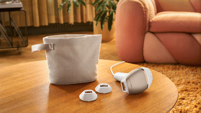 A light brown Philips Lumea machine found next to a bag. All items are sitting on a wooden table.
