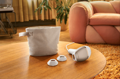 A light brown Philips Lumea machine found next to a bag. All items are sitting on a wooden table.