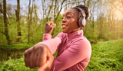 Vrouw die Philips sportkoptelefoon draagt tijdens een outdoor training, ontworpen voor comfort en stabiliteit tijdens het bewegen