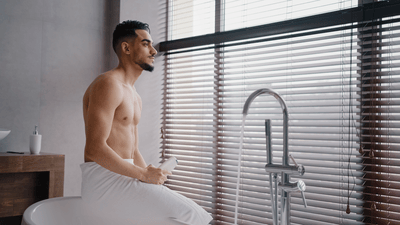 Man wrapped in towel looking out of window