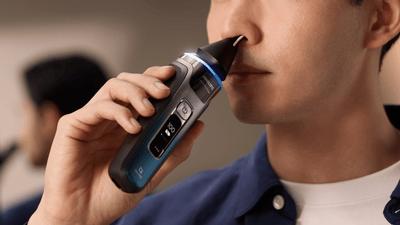 Close-up image of a man using a Philips shaver to trim his nose hair with the suitable attachment.