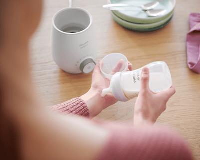 Maman testant la température du lait sur son bras