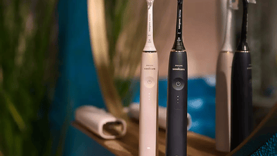 Vue de deux brosses à dents électriques Philips, une noire et une blanche, face à une fenêtre donnant sur la mer.