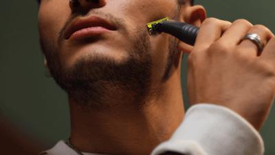 A close-up shot of a young man shaving his beard with a Philips OneBlade Pro 360.