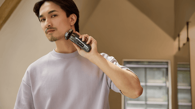 A man is shaving his beard into the musketeer style using a Philips shaver.