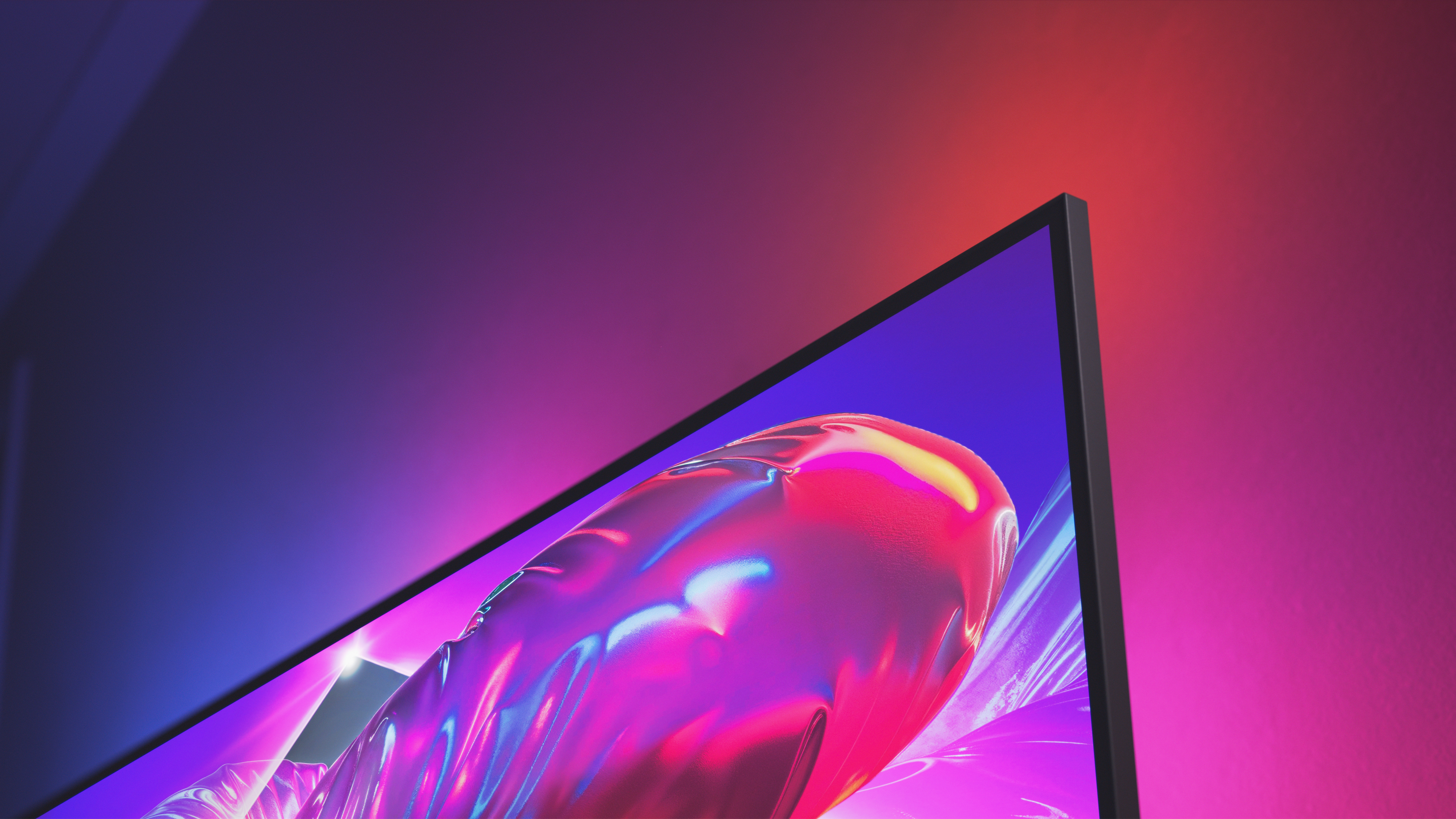 Close-up of a Philips Ambilight TV with an ultra-thin bezel, displaying vibrant pink and purple visuals while matching ambient light glows on the wall behind it.