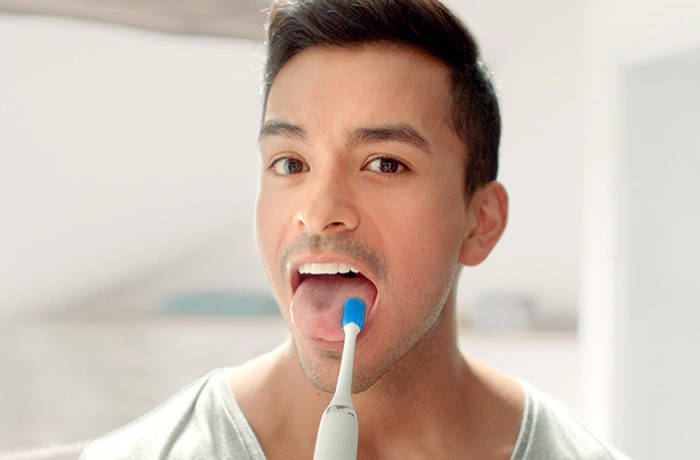 Un bărbat își curăță limba folosind o perie specială Philips.