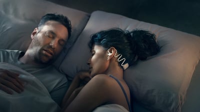 Image of a woman sleeping with Philips Sleep Headphones in to avoid disturbances while sharing a bed with a partner.
